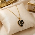 Close-up of gold leaf pendant necklace with black enamel finish and sparkling crystals. - Black Enamel Leaf Pendant Style (KN299039-SXSJ)
