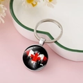 Detail view of a Canada flag maple leaf keychain on a white heart-shaped ceramic plate - Black Background Distressed Spray Paint Style (CC002398-8)