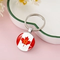 Close-up of a silver-toned Canadian flag maple leaf charm keychain with glass dome - Maple Leaf with Gold-Edged Star Style (CC002398-9)