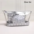 Set de 3 neceseres plateados con bolsa de PVC transparente y estuches metálicos acolchados - Set de tres piezas / Plateado