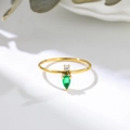 Primer plano de un anillo dorado con circón blanco redondo y gema verde en forma de pera - US 7 / Dorado/Verde