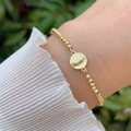 Detailed close-up of a 18K gold-plated beaded bracelet with a Virgin Mary pendant - Round Our Lady of Guadalupe Style