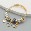 Detailweergave van de verstelbare goudkleurige bedelarmband met zwaan en hartjes - Zwart