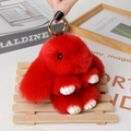Red plush rabbit keychain accessory with golden clip on a warm wooden background - Large / Red