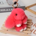 Pink plush rabbit charm with gold metal ring shown being held against a cozy home background - Large / Watermelon red