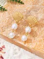 Détail de boucles d'oreilles coquillage dorées avec doubles perles sur un décor de sable marin - Boucles d'oreilles à tige en acier