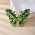 Spilla vintage a farfalla dorata con cristalli verdi su sfondo in pelle beige - Farfalla Verde Pavone