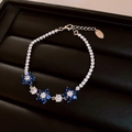 Bracelet élégant en argent avec fleurs en zircon bleu et blanc sur plateau noir. - Style Floral Bleu / Argent