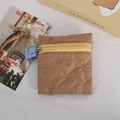 Brown heart-quilted coin purse with yellow zipper and metal ring on white fabric - Brown