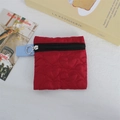 Detailed view of red heart-quilted coin purse with light blue zipper strap on table - Burgundy