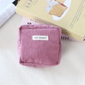 Detail of purple corduroy square pouch featuring textured fabric and brand label - Lotus Pink