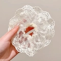 Hand met een grote witte kanten scrunchie met bloemmotief voor een elegant kapsel styling - #3 Wilgenblad Kant Melkwit Haarelastiekje - 13cm