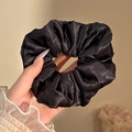 Volumineuze zwarte satijnen scrunchie met glinstering vastgehouden in de hand - #3 Elegant Zwart 12 Cm