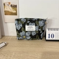 Detailed view of floral jacquard makeup bag on a wooden desk with a 2024 calendar - Blue Floral