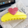 Yellow crescent hair claw with pink heart detail placed on a beige canvas bag - 13cm / Bright Yellow