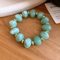 Bracelet en perles acryliques vert clair avec disques dorés sur bois clair - Bracelet / Vert