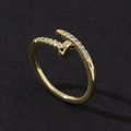 Top view of gold nail-shaped ring with white zircons on black matte background - Style 27