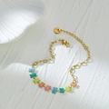 Buntes Knochen-Charm-Armband aus 14K vergoldetem Edelstahl auf weißem Steinuntergrund - Buntes Knochen Armband