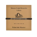 Macro detail of Libra Morse code beaded bracelet on kraft display card with black cord - Libra