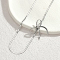 Elegant silver snake chain necklace with minimalist bow design on a white stone background - Silver (Necklace)