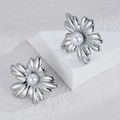 Elegantes pendientes de flor plateada con perlas barrocas en expositor minimalista - Color Acero