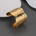 Macro detail of wide 18k gold stainless steel cuff featuring wavy textured metal finish - Wide Wave Texture Style