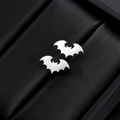 Detailed close-up of silver bat-shaped stud earrings on a black velvet display - Bat - Steel Color