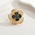 Elegant gold camellia flower ring featuring white opal effect and black gemstones - Ring Style
