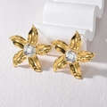 Orecchini a fiore dorati con zircone presentati su supporto bianco a onde - Oro
