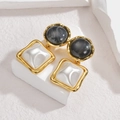 Elegant geometric gold earrings with marble and mother-of-pearl inlays on a stone surface - Black