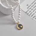 Elegant pearl necklace with a black celestial medallion featuring gold moon and star - Black