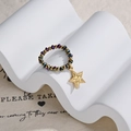 Detail of beaded ring with gold star pendant and iridescent crystals on white stand - Gold and Colorful Beaded Star Style