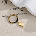 Detail of beaded stretch ring with black faceted beads and gold star charm pendant - Gold and Black Beaded Four-pointed Star Style