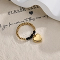 Detail of beaded ring with gold heart charm and black faceted beads on textured background - Gold and Black Beaded Heart Style
