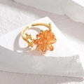 Bague dorée ajustable avec fleur en cristal orange sur un fond de pierre texturé - Orange
