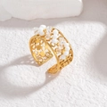 Vintage Goldring mit hohlem Design und weißen Perlen auf einem steinernen Hintergrund - Weiß