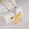 Gros plan d'un pendentif papillon doré 18 carats avec perle blanche sur chaîne en perles - Style Pendentif Papillon (OLBN2213-B)