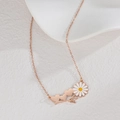 Primer plano de collar oro rosa con colgante de margarita y detalle de tres corazones - Oro rosa