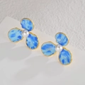 Dettaglio di orecchini a fiore con petali blu marmorizzati, bordo dorato e perla centrale - Stile Petalo Blu (E1035-lan)