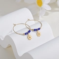 Detail of 14K gold hoop earrings with sunburst pendant and blue beads on a white stand - Dark Blue Beaded Sunburst Style (E412-taiyang-40mm)