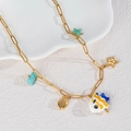 Gouden ketting met hangers van emaille vis, schelp en turkoois op een stenen bord gelegd - Emaille Vis Turquoise Zeester Stijl (N2226-D)