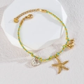 Vue détaillée du bracelet tissé à la main avec breloques dorées de baleine et hippocampe - Style Forme Étoile de Mer / Coloré