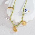 Détail du collier tressé avec pendentifs soleil et lune sur une assiette en céramique - Corde Tressée Jaune Vert Bleu-Perle en Céramique Cœur (N2228-G)