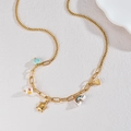 Golden stainless steel necklace with ceramic shell and turtle charms on stone background - Golden Multi-Charm (N2227)