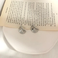 Orecchini geometrici in argento con finitura lucida su una pagina di libro vintage - Forma a Onda Irregolare / Argento