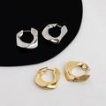 Nahaufnahme von geometrischen unregelmäßigen Metallohrringen in Gold und Silber Optik - Silber