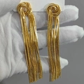 Detail von eleganten goldenen Quastenohrringen mit Schlangenketten und Knoten-Design - Gold