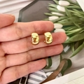 Close-up of gold-plated vintage C-shape earrings held by hand showing mirror finish - Gold Style