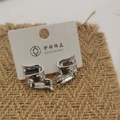 Pendientes de cinta retorcida plateados con acabado metálico brillante en tarjeta - Estilo Plateado