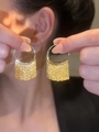 Vue détaillée de boucles d'oreilles pendantes à glands dorés portées pour un look chic - Style Plaqué Or 18K / Doré